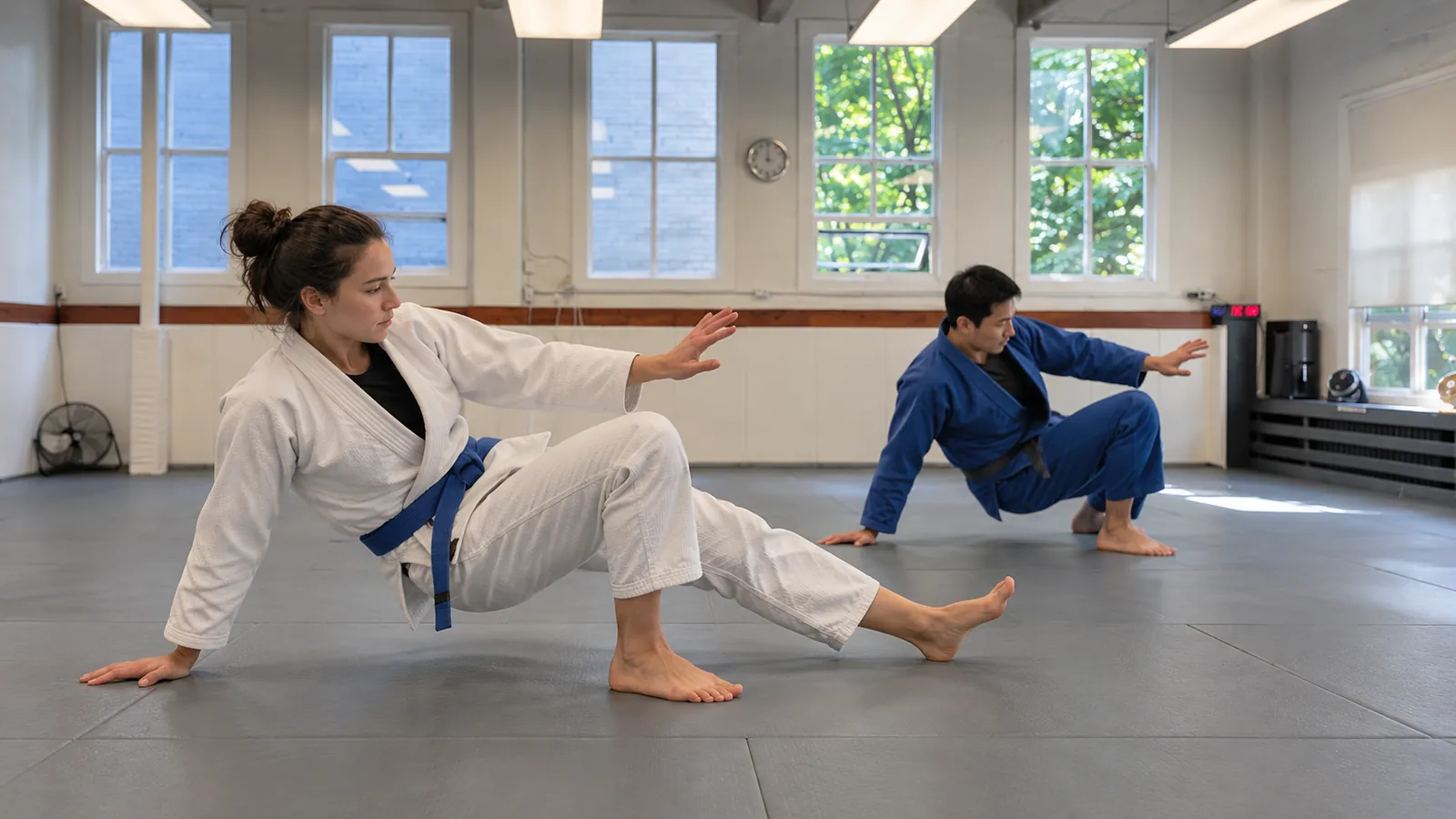 Two students practise getting back to their feet safely from the mat