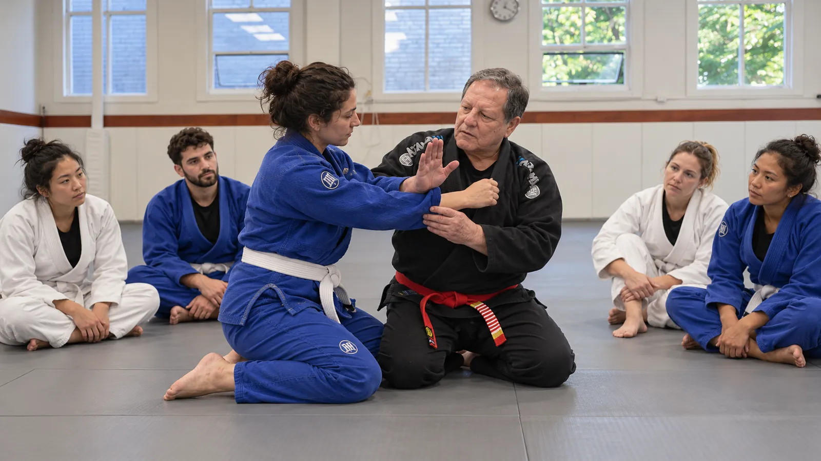 An instructor demonstrates a technique with a female student in a mixed class