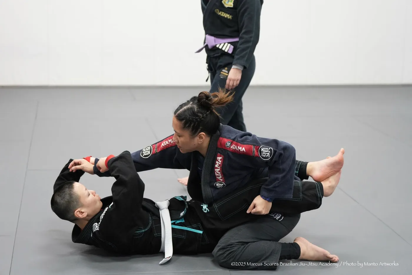 A coach guiding a young student through a technique on the mats in Vancouver